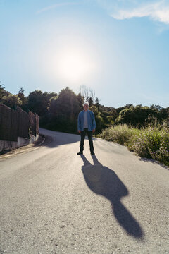 Senior man standing on road, shadow