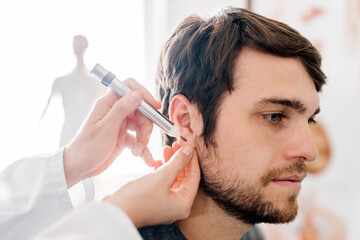 Female alternative practitioner giving man acupuncture with akupen in ear