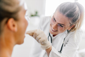 Female doctor examining female patient with tongue depressor