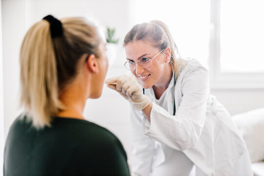 Female doctor examining female patient with tongue depressor