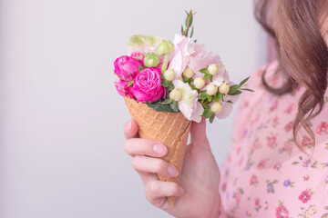 Women in vintage dress holding ice cream waffle cone with pink roses and hydrangea .Floral composition of beautiful spring fresh flowers isolated indoor. Florist at work.Copy Space.Food photo.