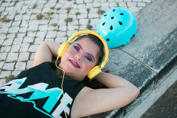 Teenager girl with down syndrome wearing 8s colorful makeup and listening to music with yellow headphones