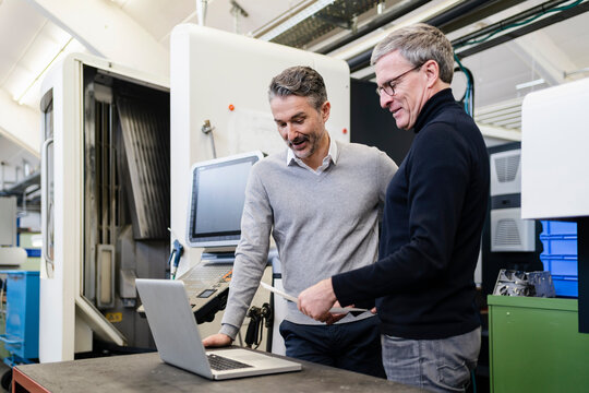 Male supervisors discussing over laptop in factory