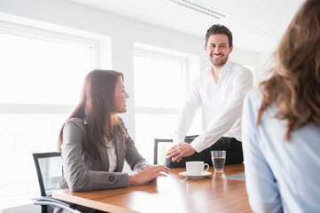 Happy business colleagues discussing in brightly lit board room