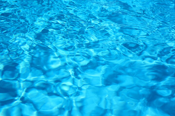 Texture of blue water in swimming pool as background, closeup