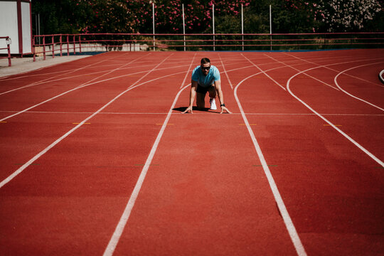 Male athlete in starting position on tartan track