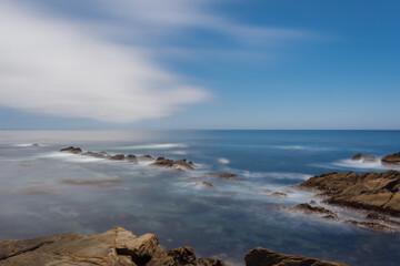 Fototapeta na wymiar A long exposure of a rocky seashore of Pacific ocean in California. 