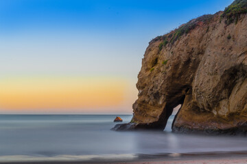 A beautiful view of a rock at Año Nuevo State Park, California, as if an elephant drinks water in the sea with the colorful sky background in the Summer evening. Long exposure.