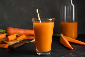 Glass of freshly made carrot juice on black table