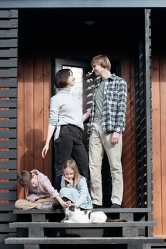 Family with cat on porch steps outside house during sunny day, Tarusa, Russia