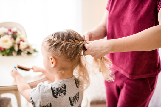 Woman braiding girl's hair at home