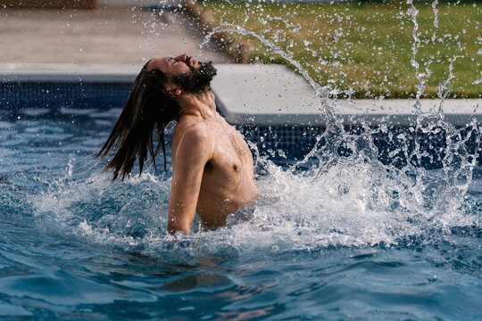 Bearded Man In Swimming Pool Splashing With Water