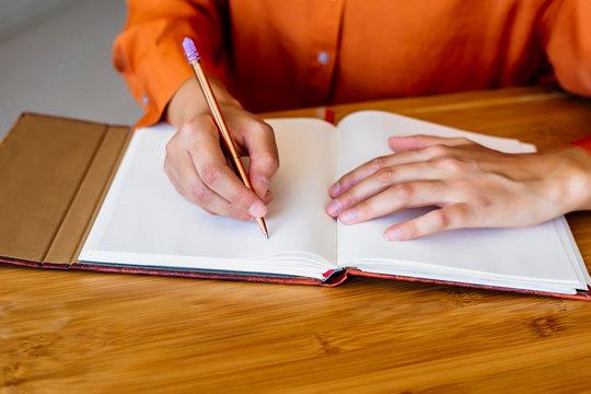 Close-up of woman sitting at desk taking notes