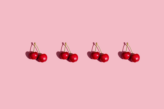 Row of fresh cherries on pink background