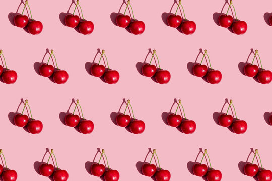 Pattern of fresh cherries on pink background