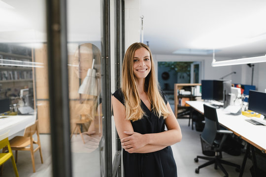 Young businesswoman standing in office, with arms crossed