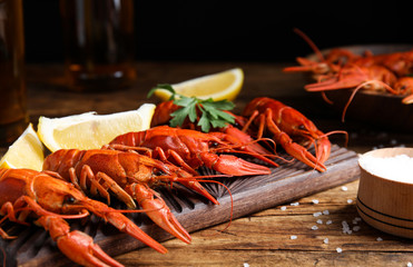 Delicious red boiled crayfishes on wooden table, closeup
