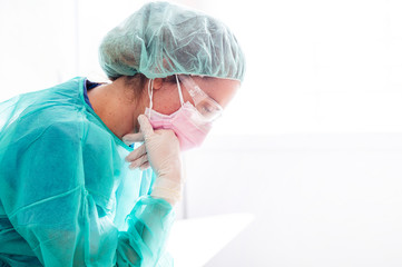 Close-up of sad doctor wearing protective workwear sitting against window