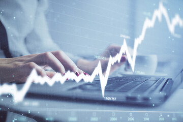 Multi exposure of woman hands typing on computer and financial graph hologram drawing. Stock market...
