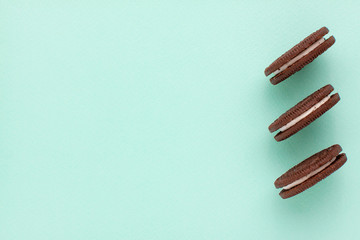 Sweet brown cookies with white cream inside on bright blue background. Close up with copy space. Homemade and bakery concept