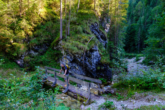Austria, Tyrol, Steinberg am Rofan, Male backpacker admiring surrounding mountain forest from small narrow bridge