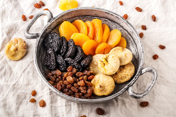 Assorted dried fruits in iron bowl, top view.