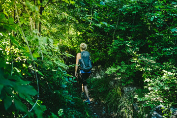 Woman with backpack hiking amidst trees and plants in forest, Lecco, Italy
