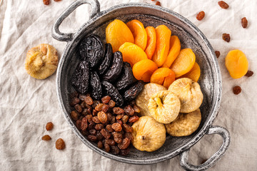 Assorted dried fruits in iron bowl, top view.