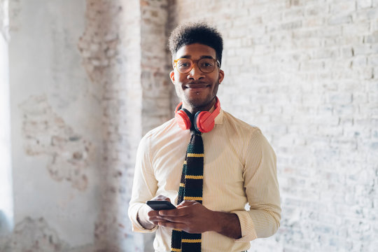 Portrait of smiling young man holding smartphone in loft