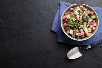 Delicious cold okroshka with kvass served on black table, flat lay and space for text. Traditional Russian summer soup