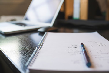 Laptop and notepad with pencil on desk in office