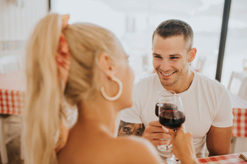 Fototapeta na wymiar Happy young couple toasting wineglasses in restaurant