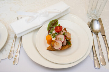 A healthy dish with meat and vegetables. Healthy food in a restaurant. Table setting with white plates. First course