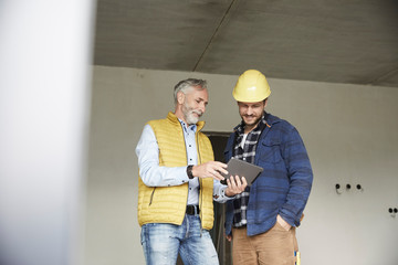 Architect and worker sharing tablet on a construction site