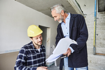 Architect and worker discussing building plan on a construction site