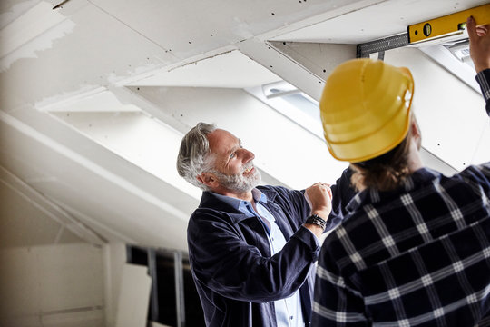 Architect and worker measuring window on a construction site
