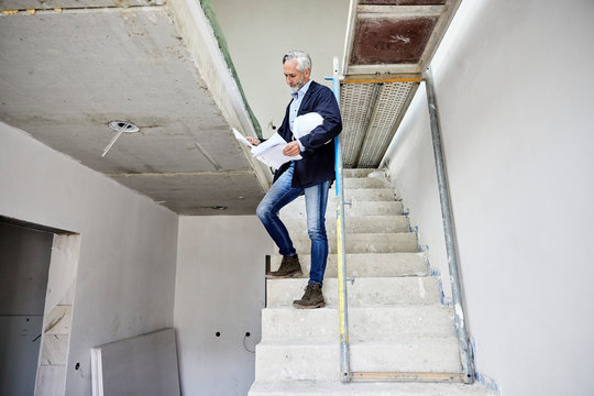 Architect holding building plan on a construction site