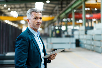 Mature businessman holding tablet in a factory