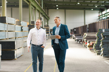 Two businessmen having a meeting and walking in a factory
