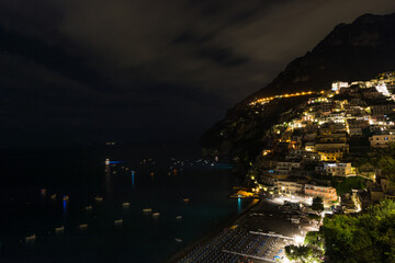 View of Positano city and beach at night during a cloudy evening with some stars, Amalfi coast, South of Italy.