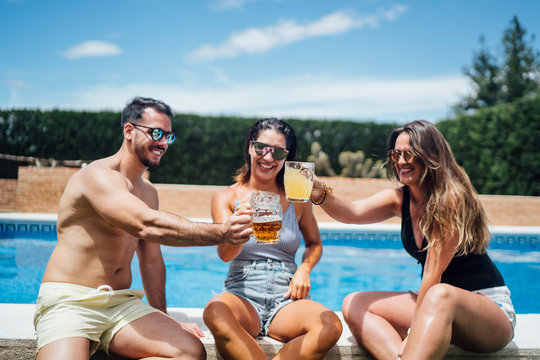Friends during pool party toasting with beer