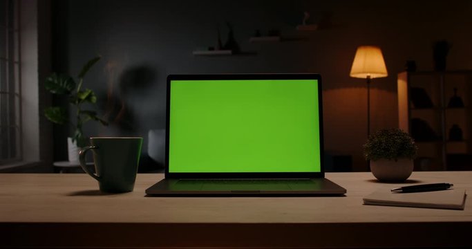 Close up shot of modern chroma key green screen laptop computer set up for work on desk at night - remote work, technology concept 4k video template