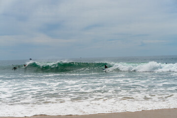 Surfers on the sea, turquoise water, blue sky. Arugam Bay, Sri Lanka. Portrait format