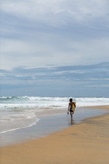 surfer on the beach, sunny day and cloudy sky, Arugam Bay, Sri Lanka