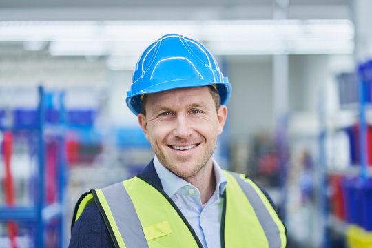 Happy male supervisor wearing hardhat and reflective clothing in factory