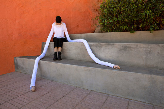 Woman with long artificial hands sitting on concrete steps
