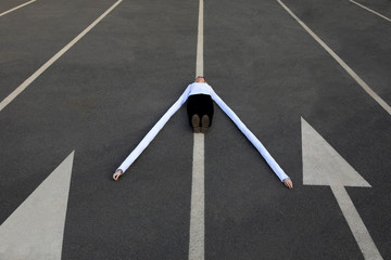 Woman with long artificial hands lying amidst arrow symbols on road