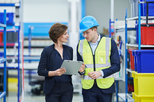 Supervisor And Female Manager Discussing Over Clipboard In Factory