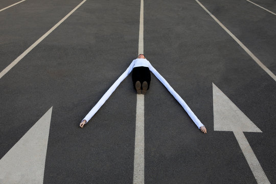 Woman with long artificial hands lying amidst arrow symbols on road