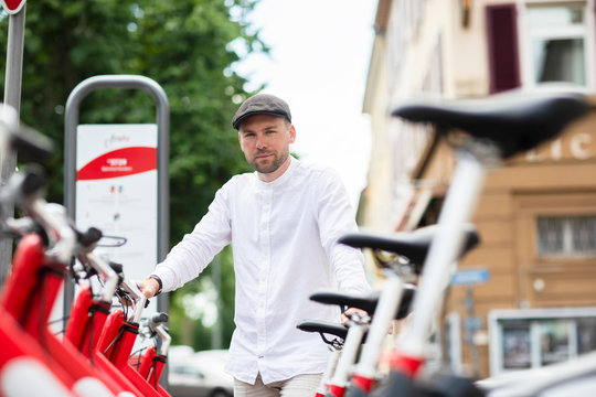 Confident mid adult man standing at bicycle parking station in city